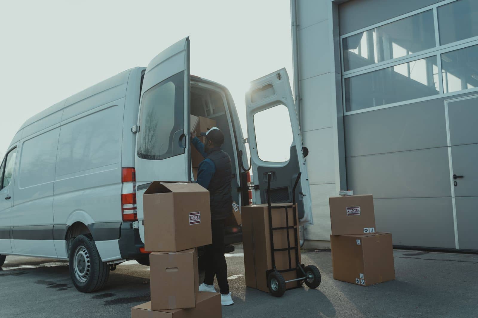 A courier loading cartons into a van outside the warehouse